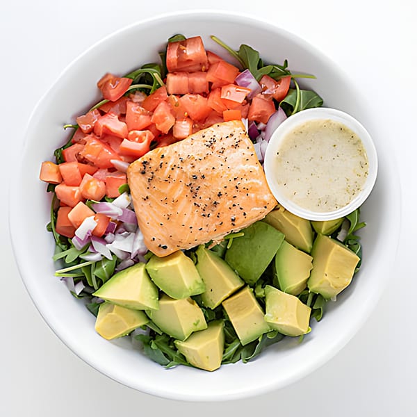 Holy Bowly's healthy salmon salad with avocado, tomatoes, red onion, and dressing.
