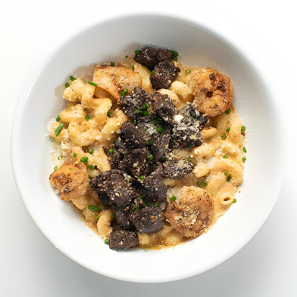 Holy Bowly's mac and cheese with shrimp and dark, chunky mushrooms, garnished with chives.
