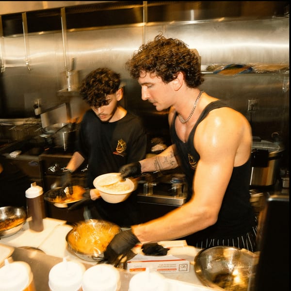 Two Holy Bowly chefs in a busy kitchen preparing healthy food bowls with fresh ingredients.