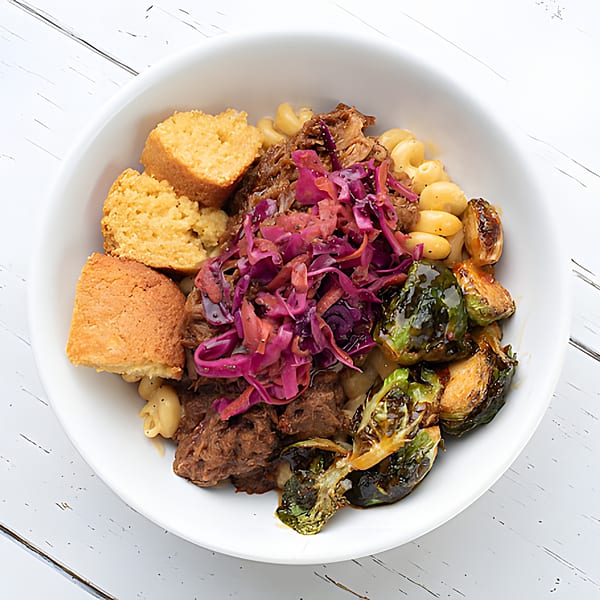 Holy Bowly's healthy bowl with pulled pork, macaroni, cornbread, roasted Brussels sprouts, and red cabbage.