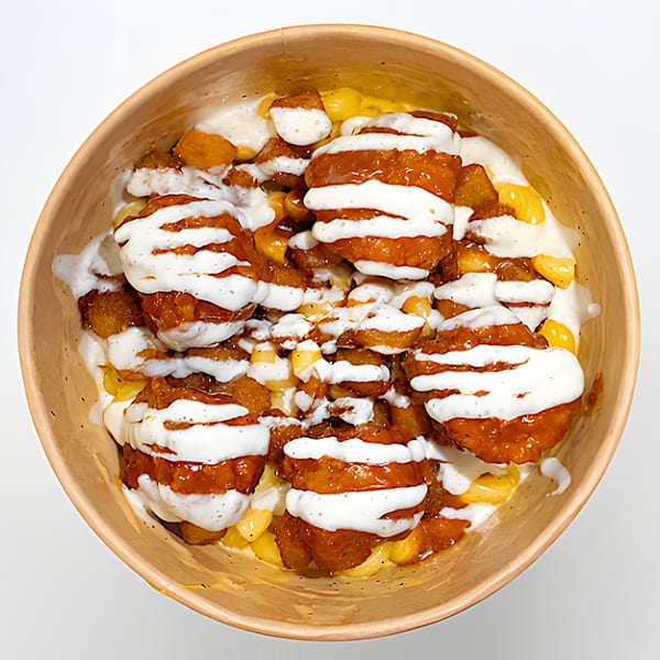 Holy Bowly's healthy bowl with crispy chicken, corn, and creamy white sauce in a brown bowl.