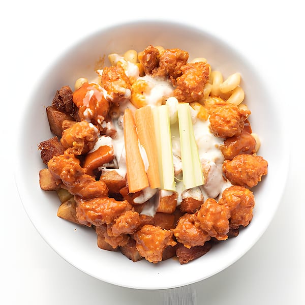 Holy Bowly's Buffalo Chicken Mac and Cheese bowl with carrots and celery sticks.