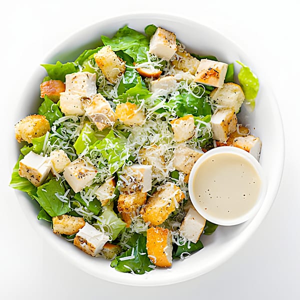 Holy Bowly's Caesar salad with grilled chicken, croutons, parmesan, and a side of dressing.
